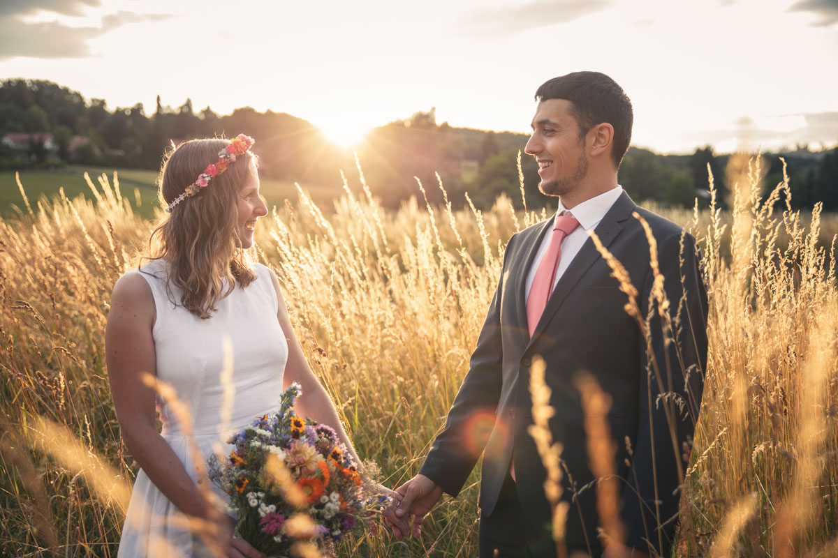 Portrait of Martina and Michele in a field with yellow grass and the sunset in the back