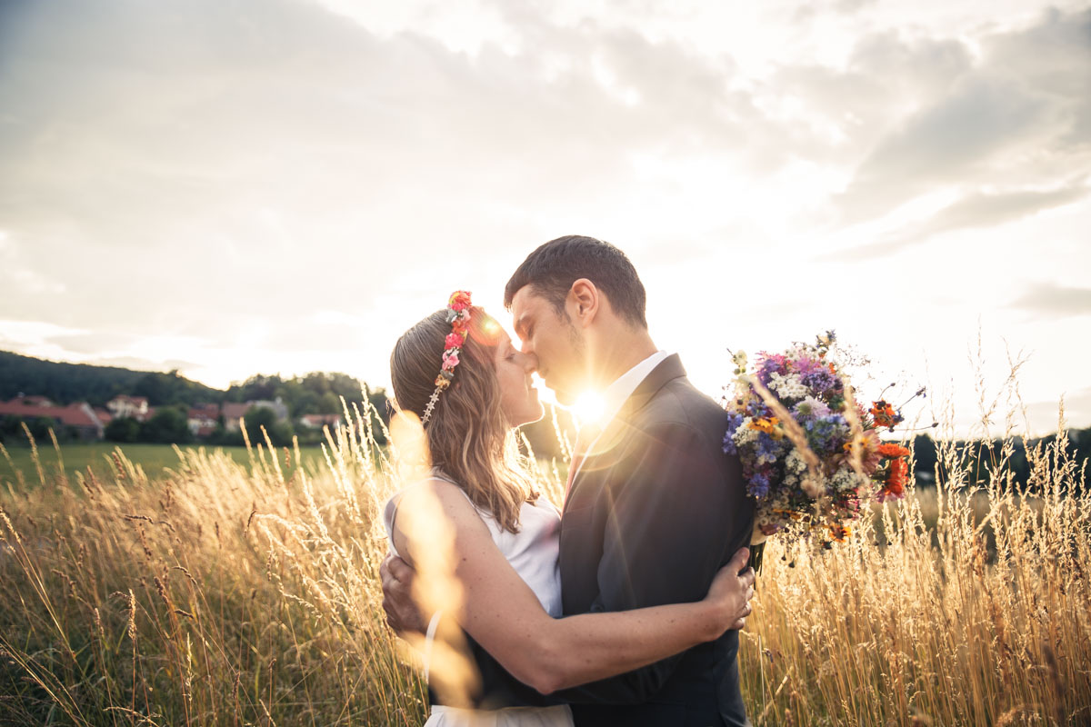 Portrait of Martina and Michele in a field with yellow grass and the sunset in the back